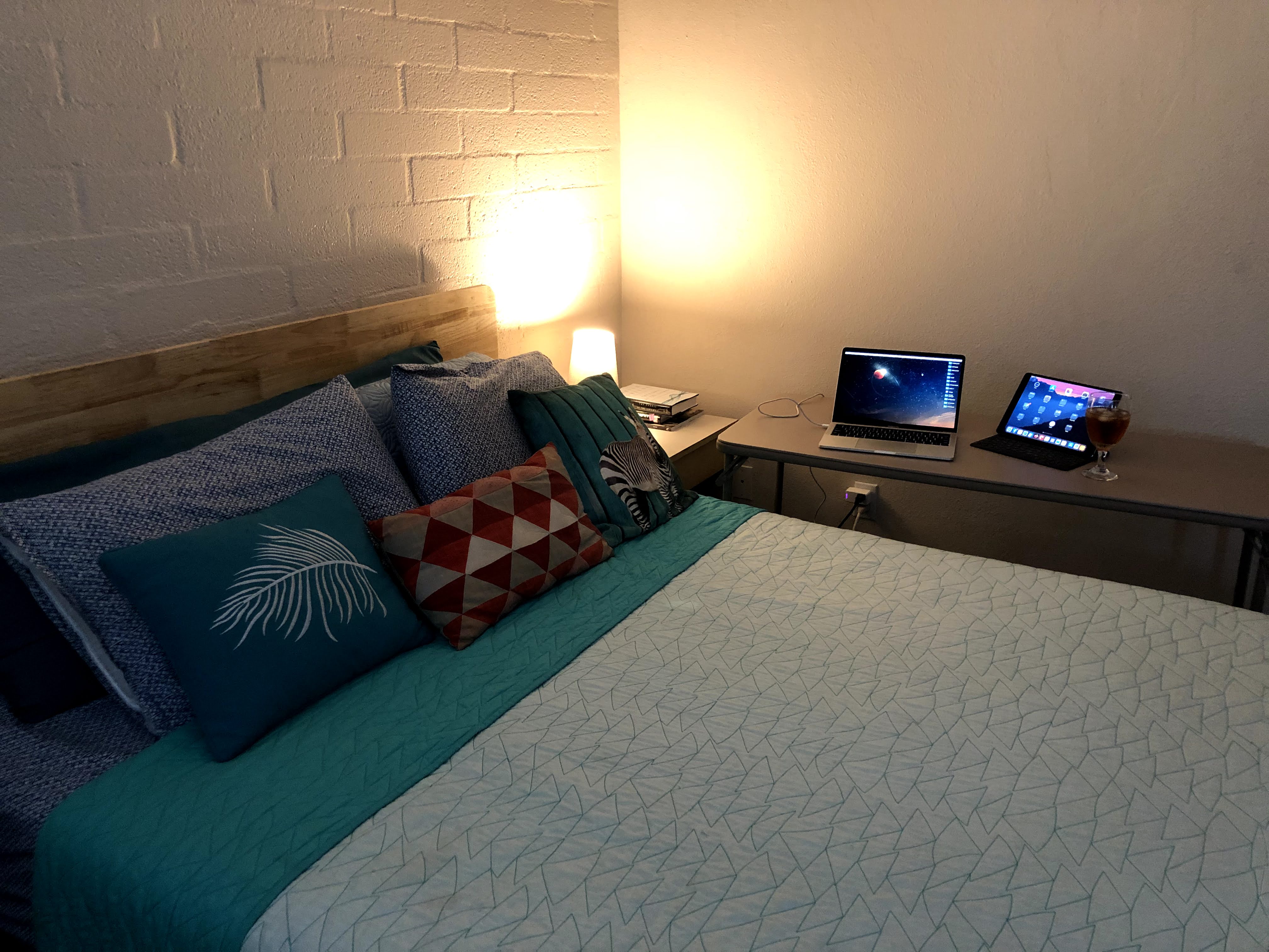 Bed, card table with laptop, iPad and glass of iced tea.